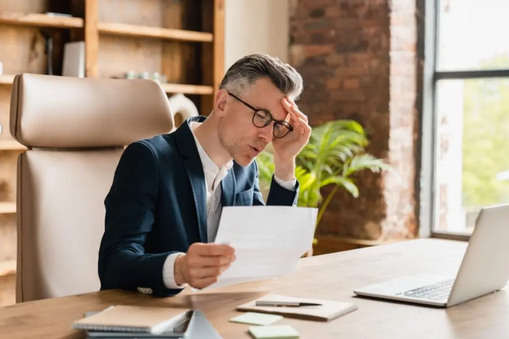 man in glasses reviewing interest rates of the debt management plan written on the paper