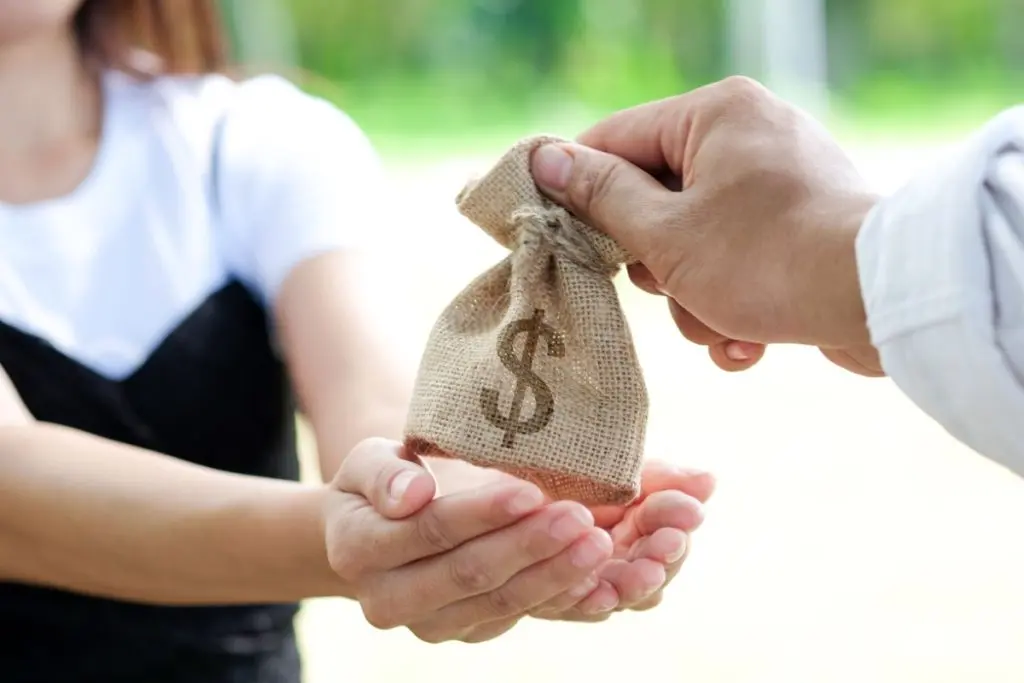 hand giving a bag of money to a woman