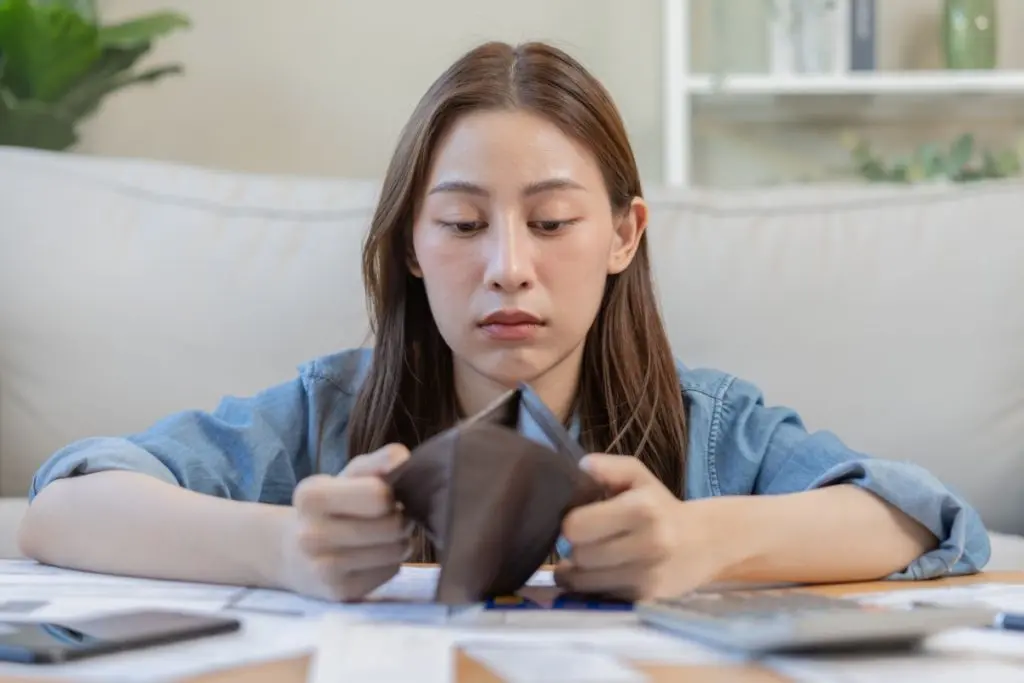 woman sadly looking at the empty wallet