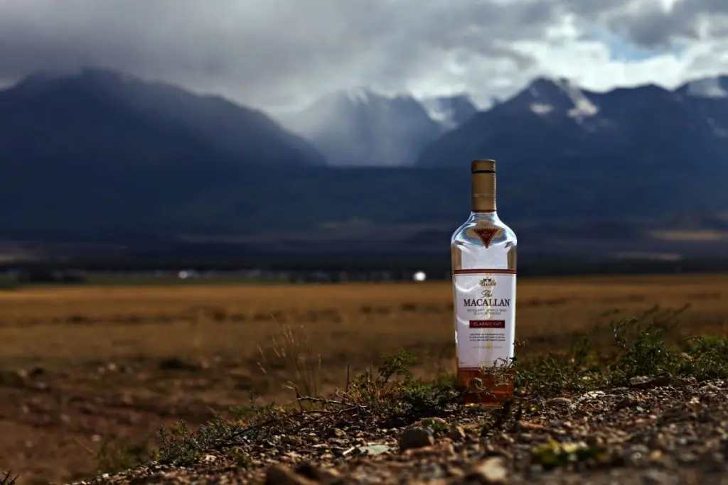 Macallan whisky bottle half full with mountains in the background