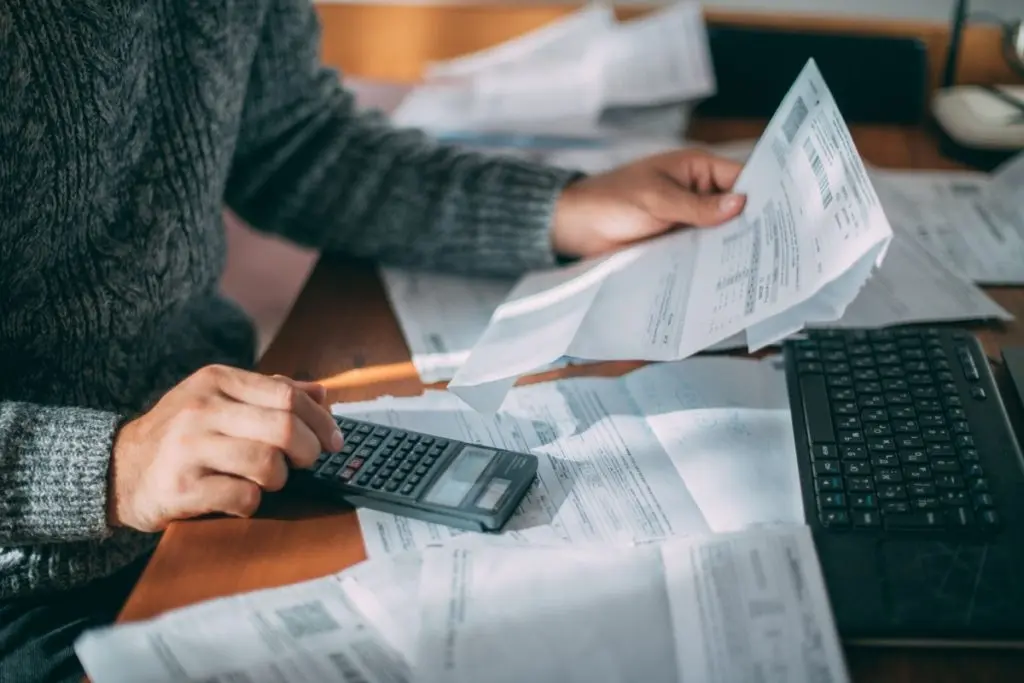 men's hands holding bills and calculator