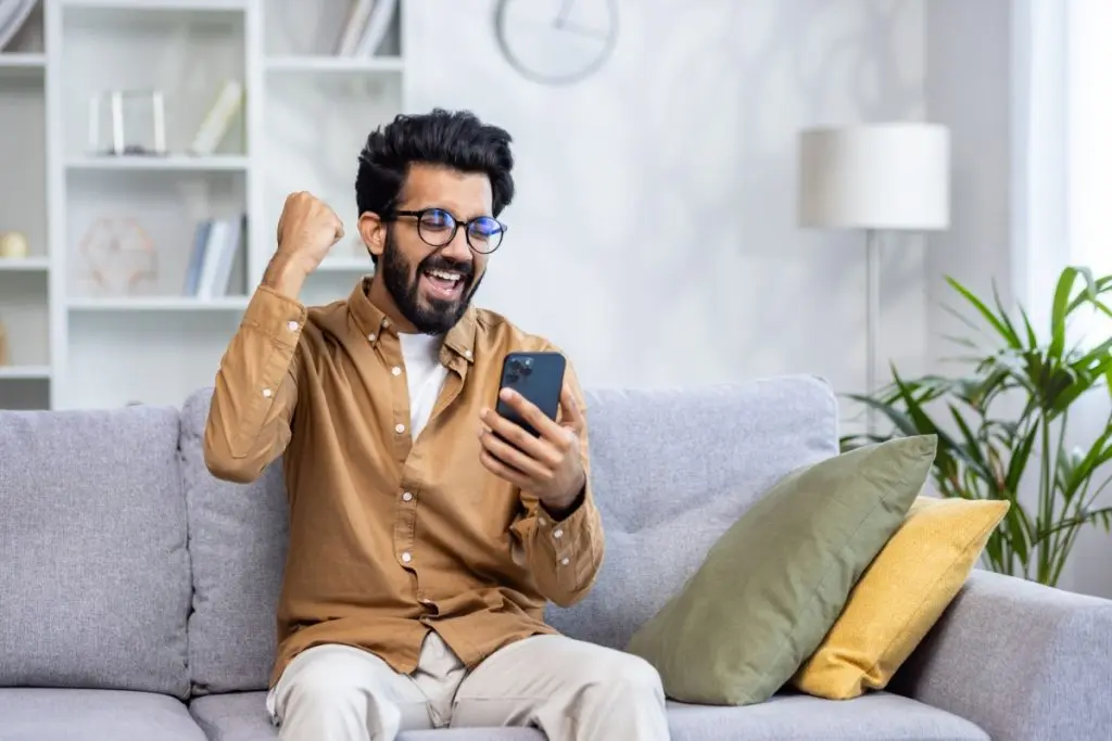 smiling man looking to a phone with approved loan