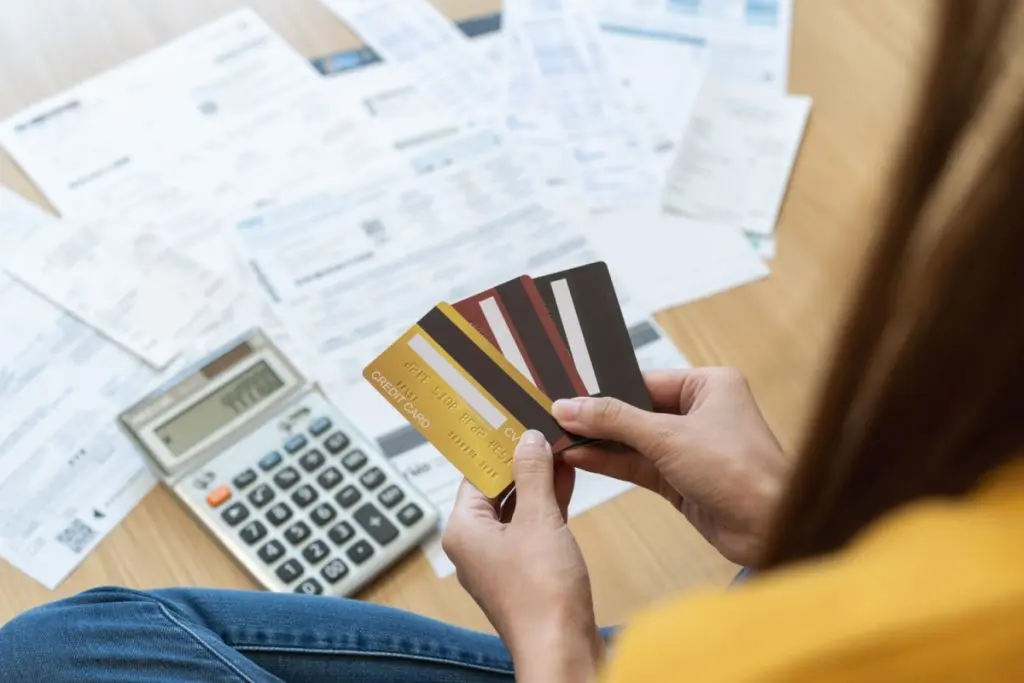 woman holding credit cards near bills