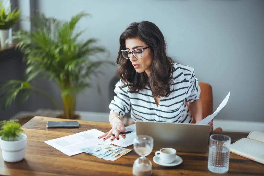 Woman in eyeglasses counting how to pay off debt