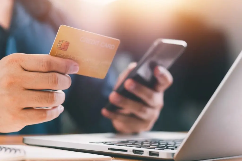 man's hand holding credit cards and phone