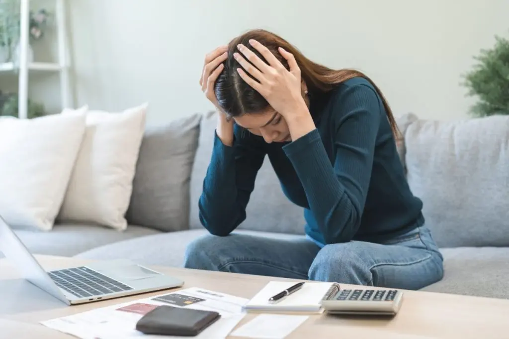 woman holding head with her hands analysing consequences of bankruptcy 