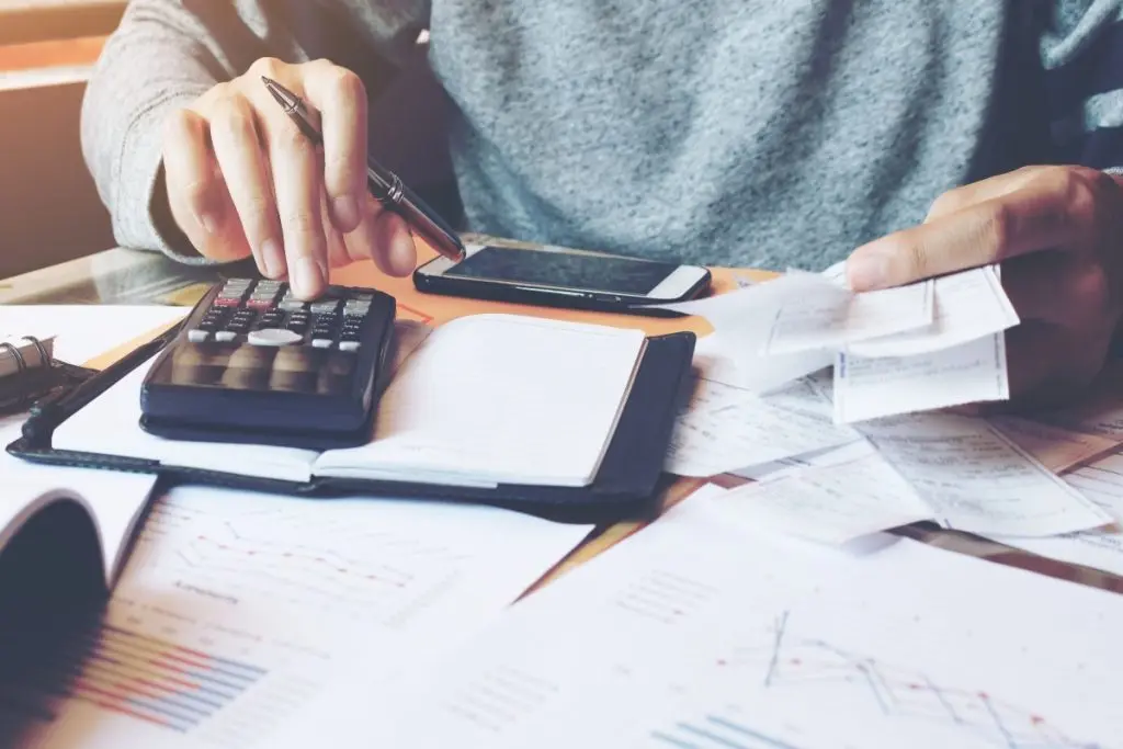 Man with calculator and paychecks counting 