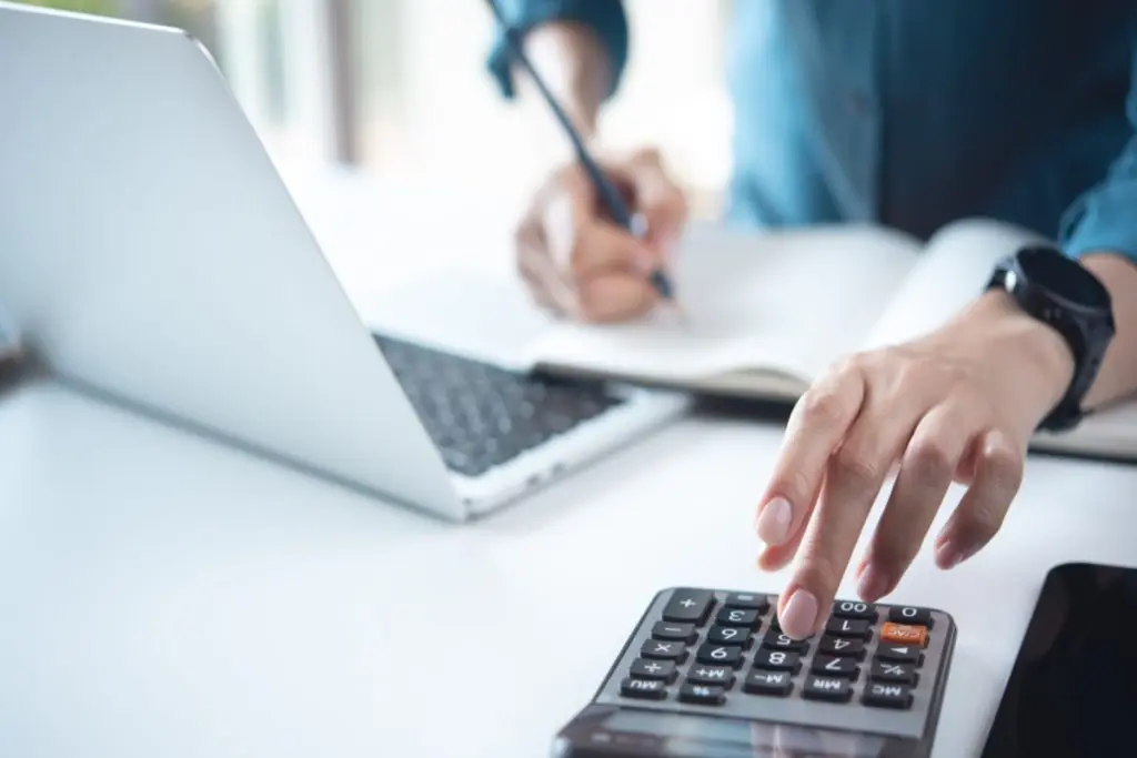 woman writing out budget on laptop