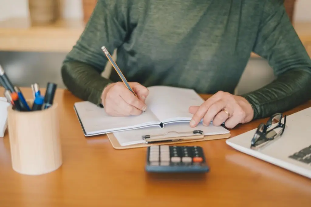 hands of lady writing down expenses