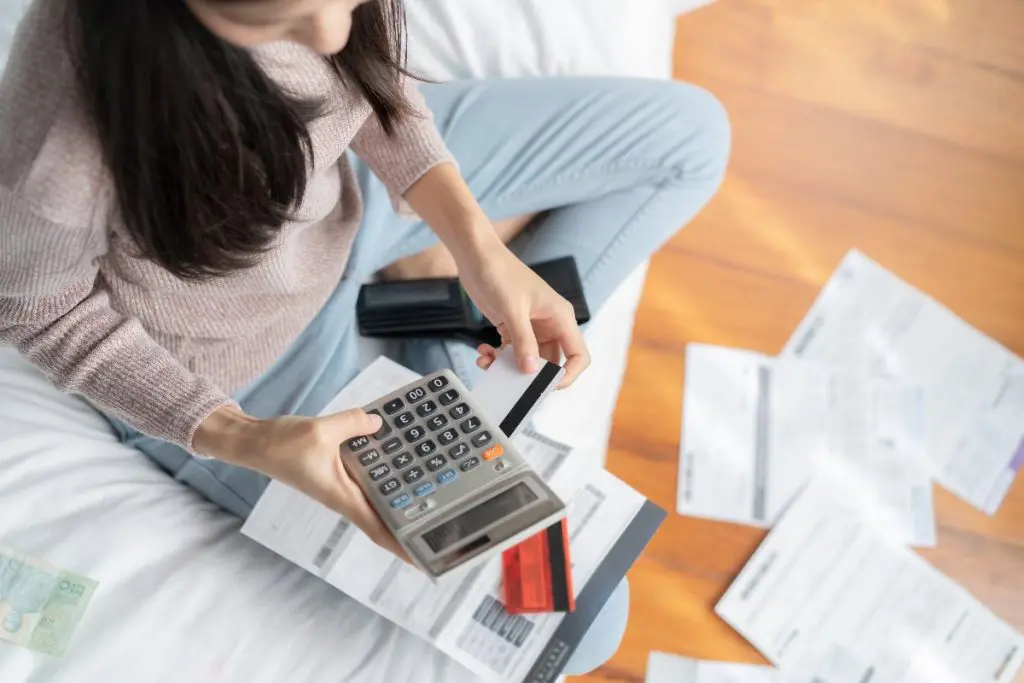 Overhead view of young adult calculating credit card debt