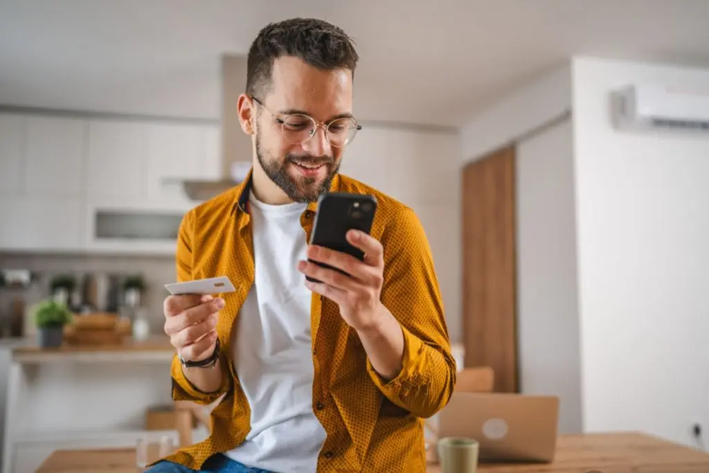 man in orang shirt checking credit score on his phone