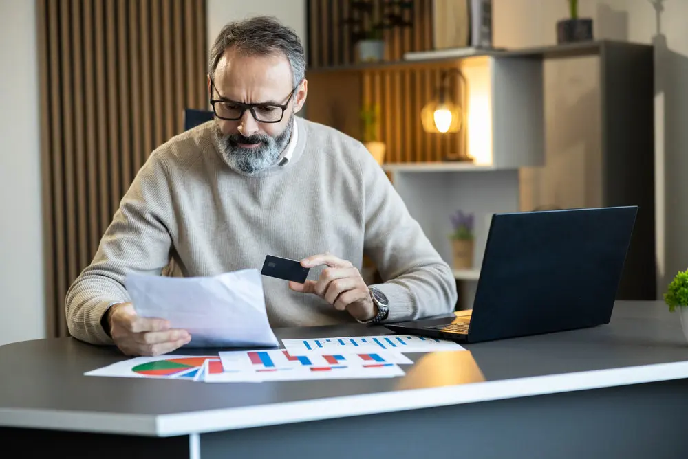Man reviewing financial information while managing a credit-card account at home