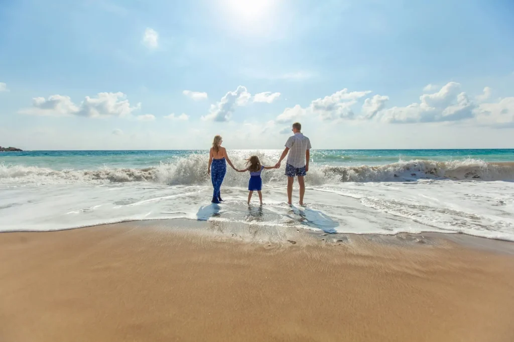 family of three standing on the seaside