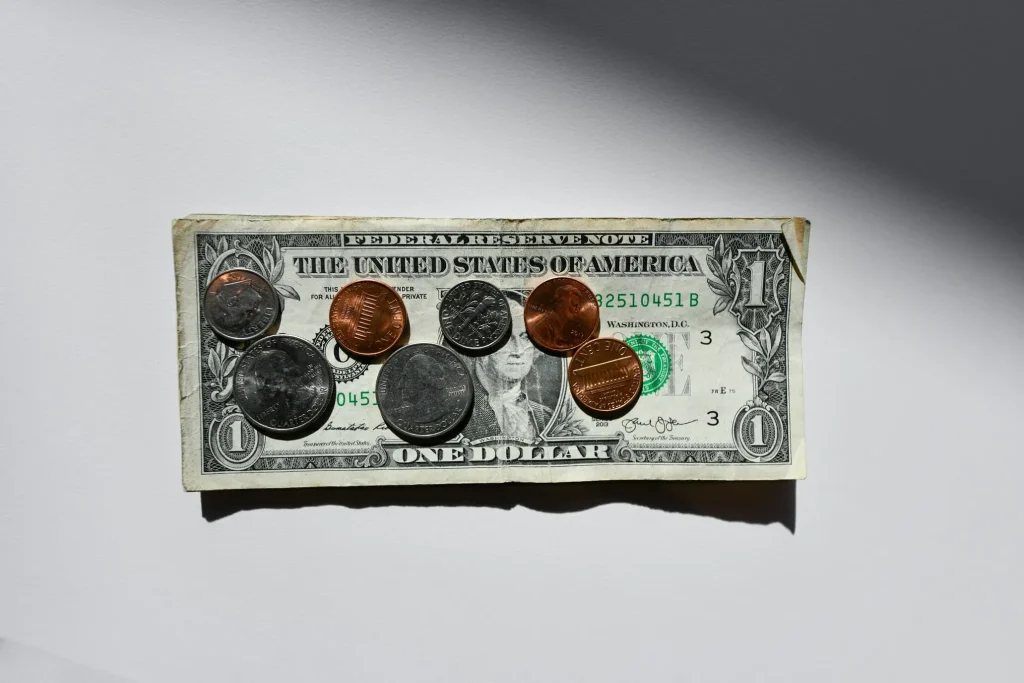 silver and copper round coins in dollar baknote