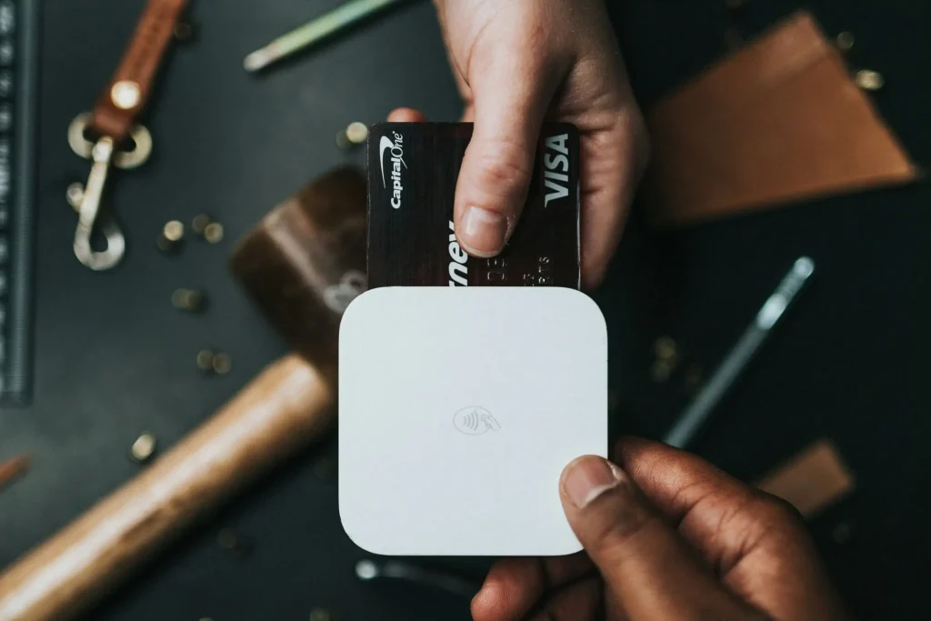 person holding credit card and white device