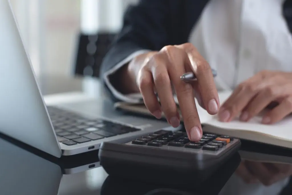 man's hand with a pen pressing a button on calculator to count expenses