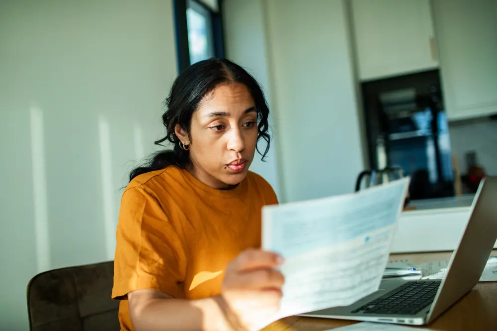 Woman reviewing financial documents and household expenses at home